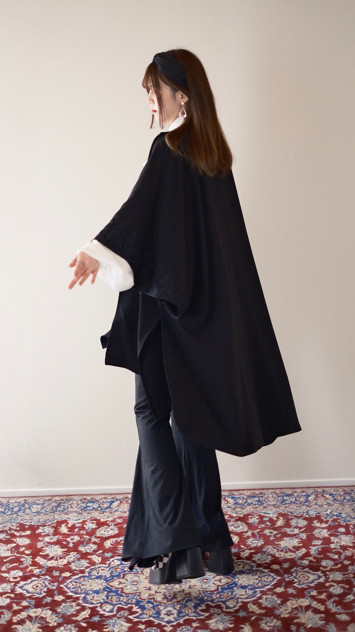 行間斗篷罩衫側面細節，展示自然垂墜感與層次