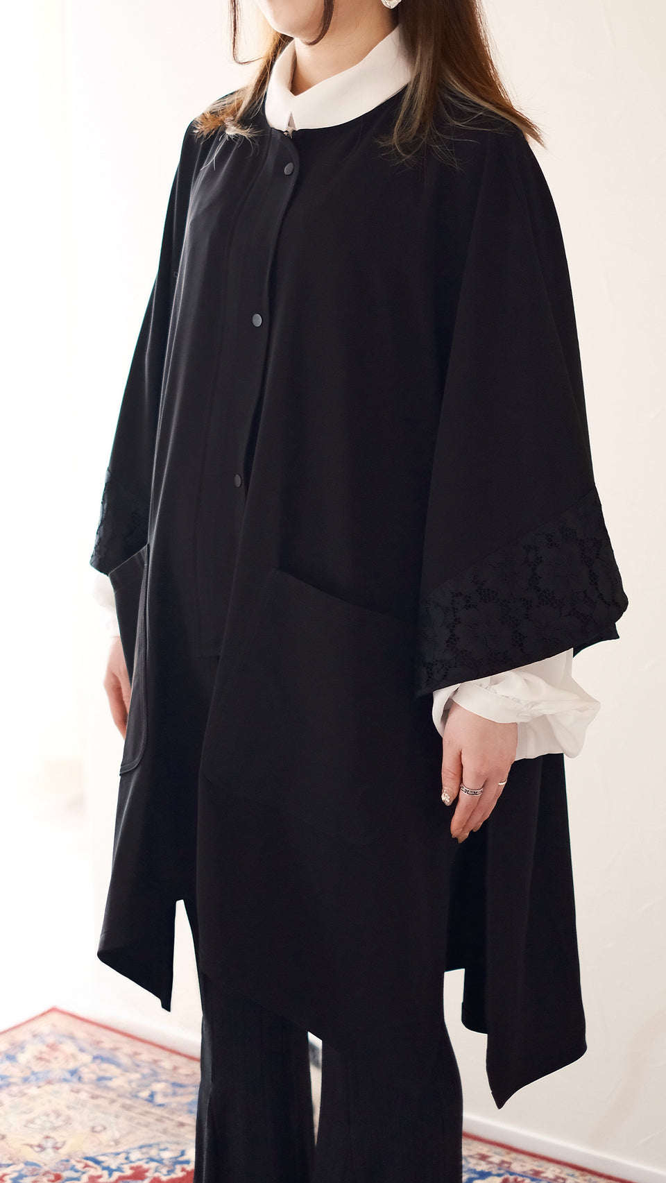 行間斗篷罩衫袖口蕾絲滾邊細節，增添女性柔美